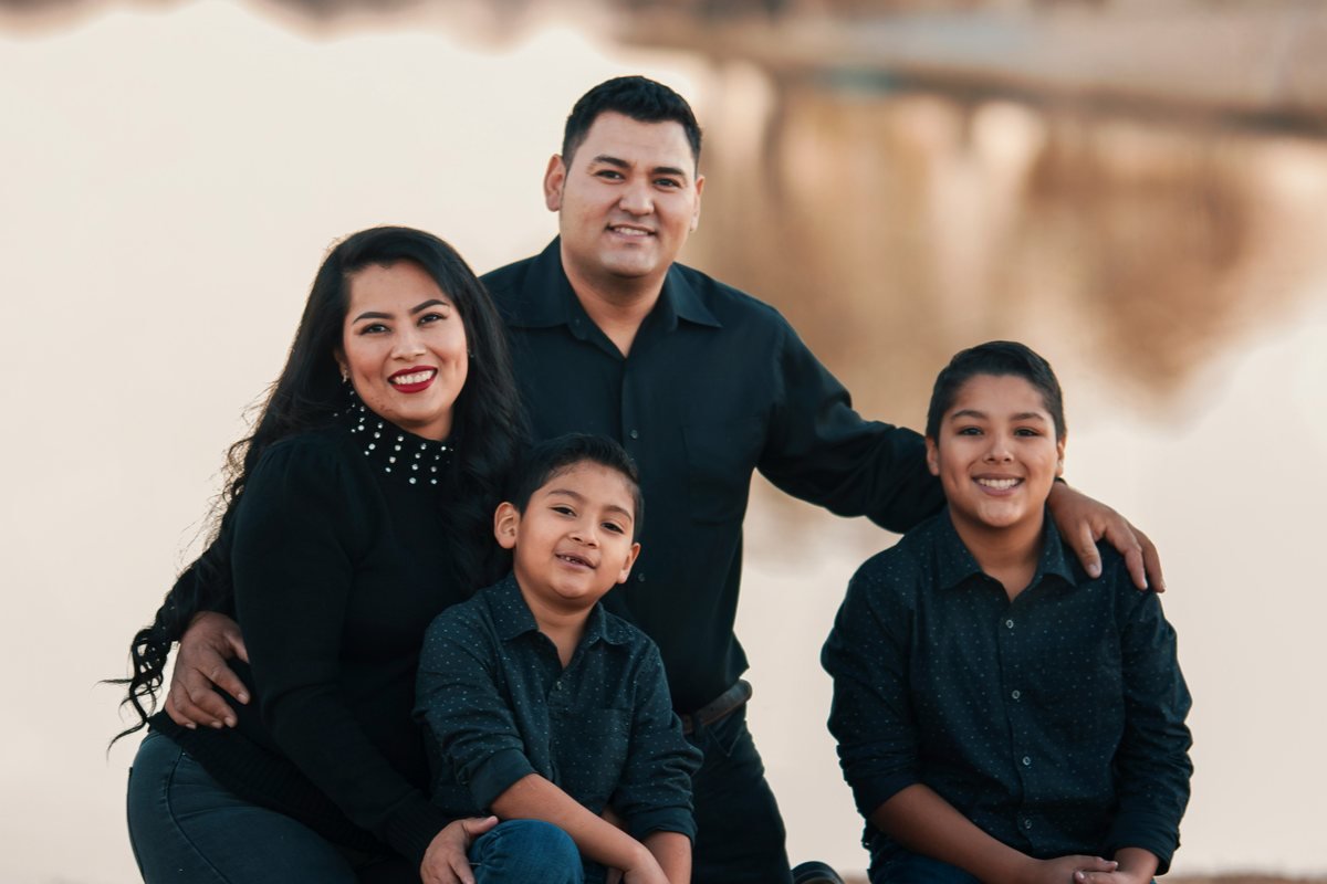 A family of four sitting together outdoors by a lake
